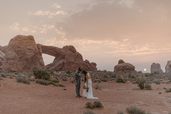 bride showing off her shoes to her husband  in arches national park