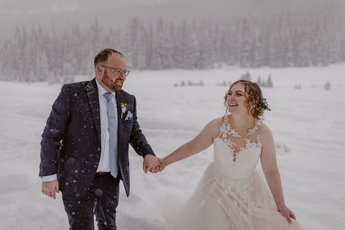 Bride and groom running in the snow on their snow elopement day