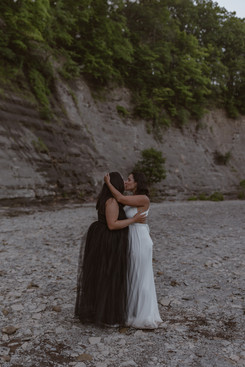 lesbian couple kissing in black and white wedding dresses on their elopement