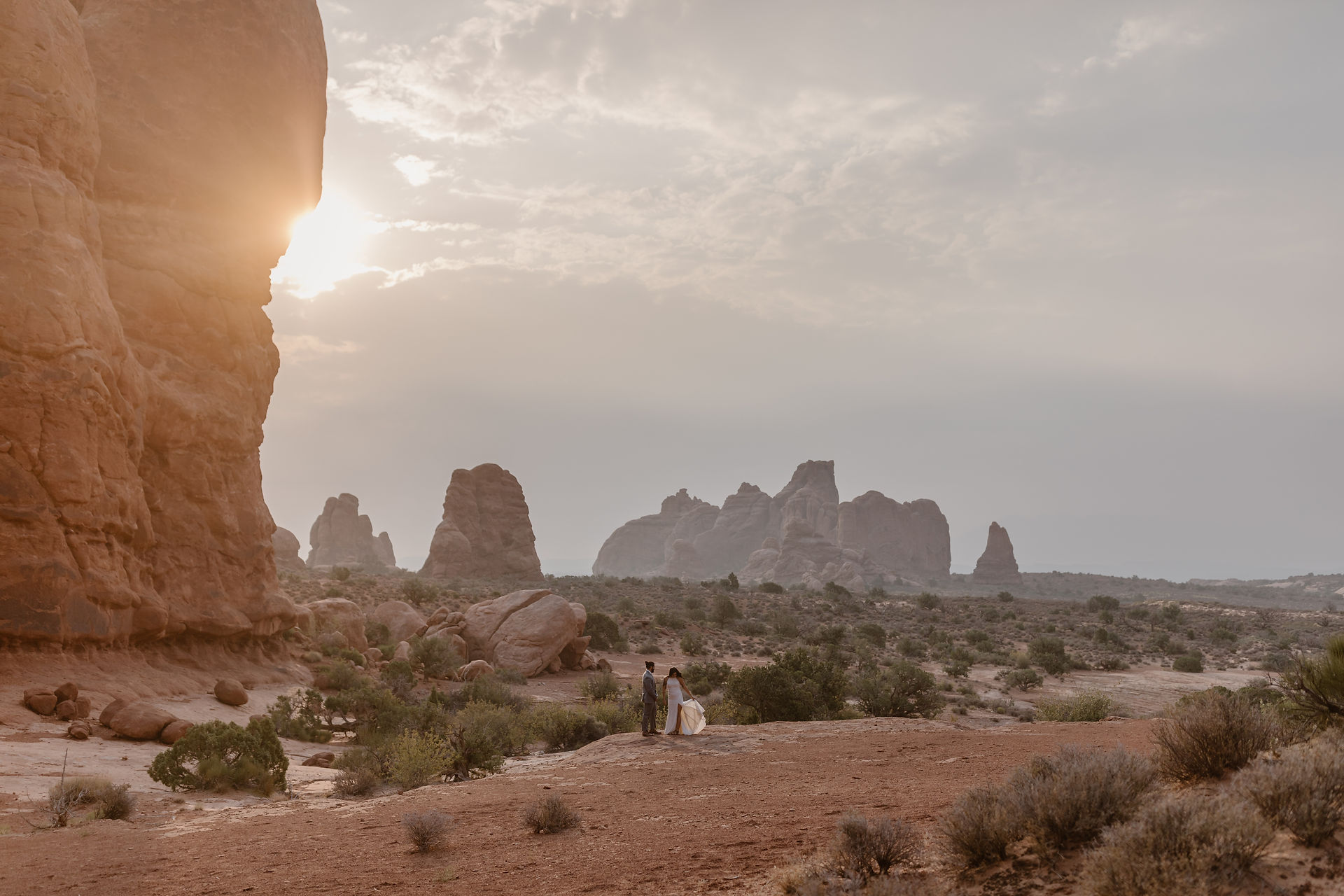bride and groom standing in the desert during sunrise in arches national park 
