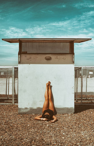 Retrato de mujer recostada en las piedras con las piernas levantadas hacia arriba y apoyadas en una cabina.