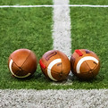 Three footballs sitting on a football fi