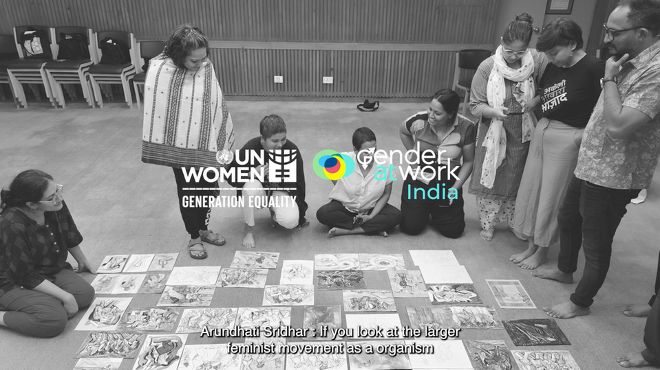 A bunch of collaborators and facilitators from the Feminist Youth Programme by UN Women (India) and Gender At Work (India) standing around each other and looking at some artwork spread around on the floor.