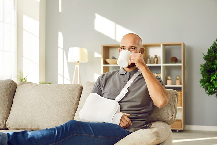 Happy bald man with broken arm drinking