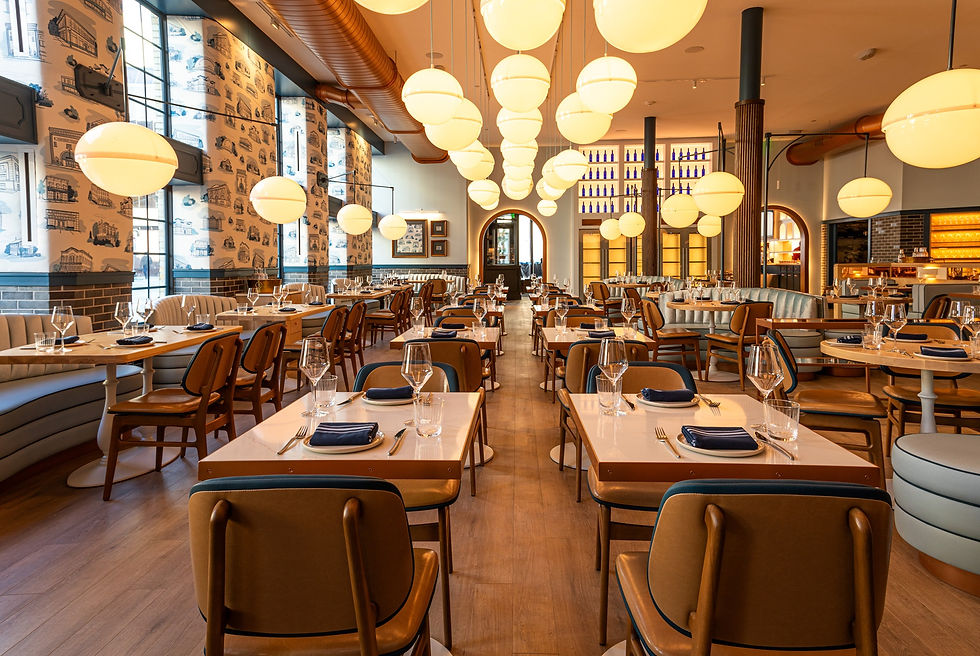 Elegant empty restaurant dining room with globe lights, set tables, blue-and-tan decor, patterned walls, and warm amber glow