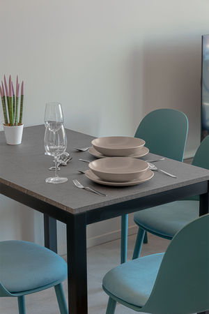 Tavolo apparecchiato con piatti e bicchieri, sedie azzurre. Fotobnb (B&B)
