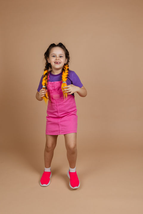 active-indulging-little-girl-touching-two-kanekalon-pigtails-dancing-looking-camera-smilin