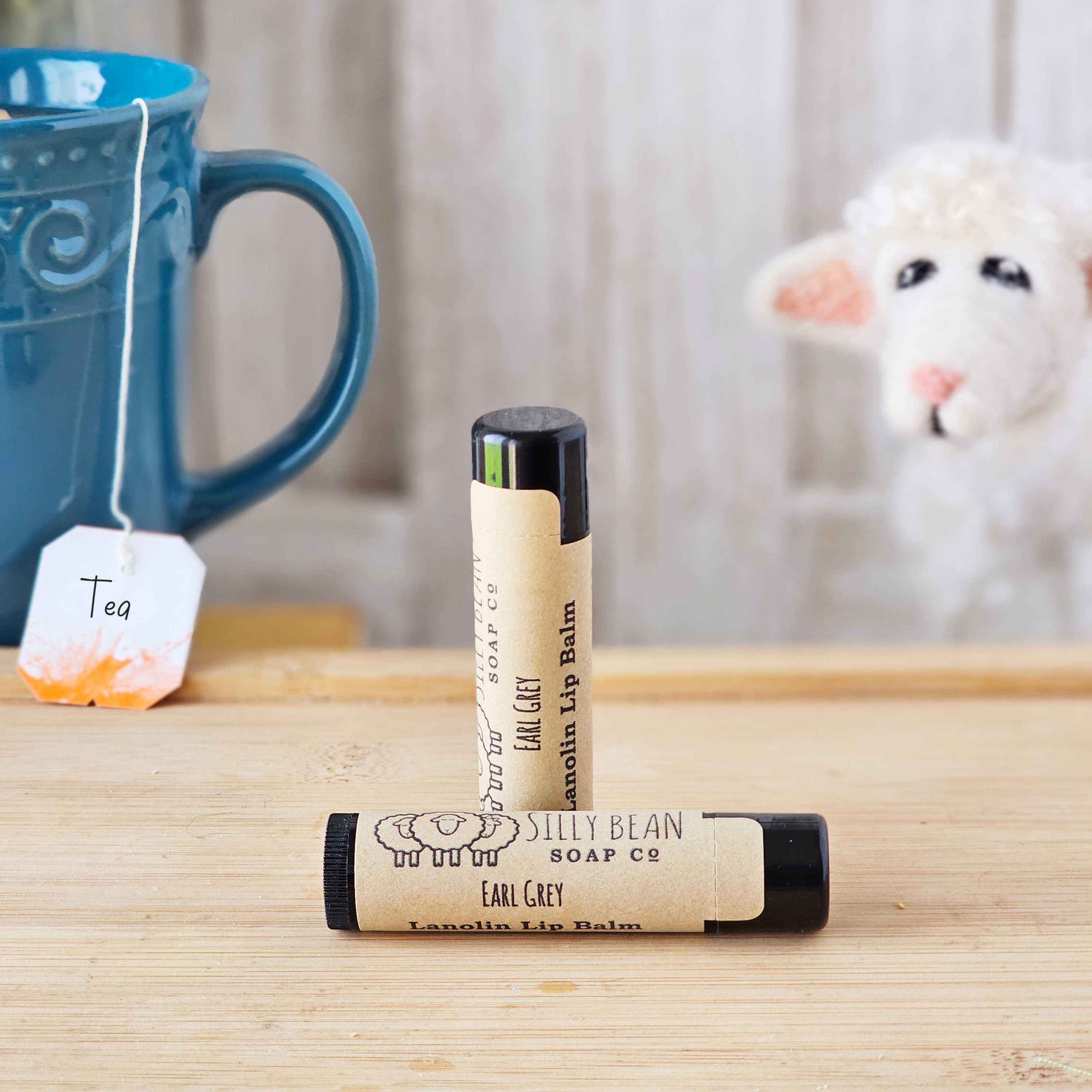 Two tubes of lanolin lip balm next to a cup of tea
