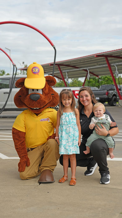 Sam The Bear and family pose in front of Sam's Xpress Car Wash.
