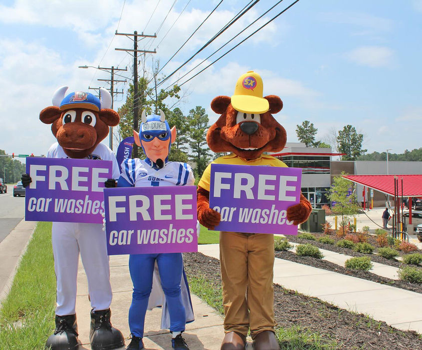 Mascots hold signs: FREE car washes. Sam The Bear promotes Sam’s Xpress Car Wash.