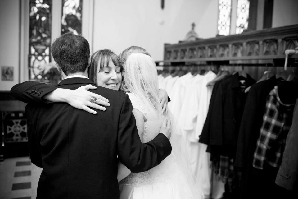 Wedding planner hugging couple in church