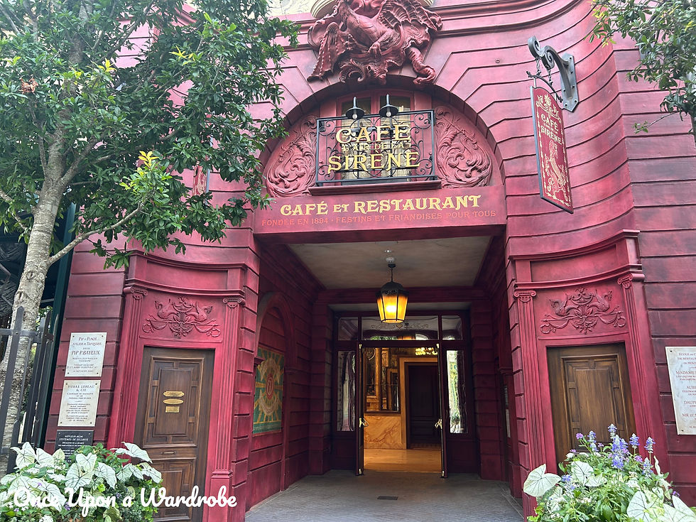 Entrance to Café de la Sirène inside The Wizarding World of Harry Potter – Ministry of Magic at Epic Universe, showcasing a deep red façade, ornate carvings, and Parisian café details.