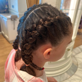 side view of a young girl's double French braid hairstyle done at the Untangled Salon aboard the Disney Wish or Disney Treasure, showcasing clean, professional styling in the Rapunzel-inspired space.