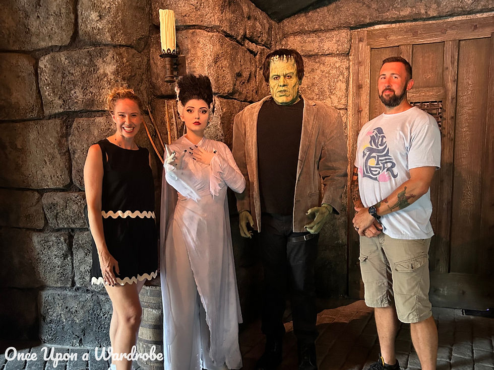 Meet and Greet – Frankenstein & Bride
Ashlie & her husband posing with Universal Monsters characters Bride of Frankenstein and Frankenstein’s Monster inside Darkmoor, with a stone castle backdrop and gothic lighting.