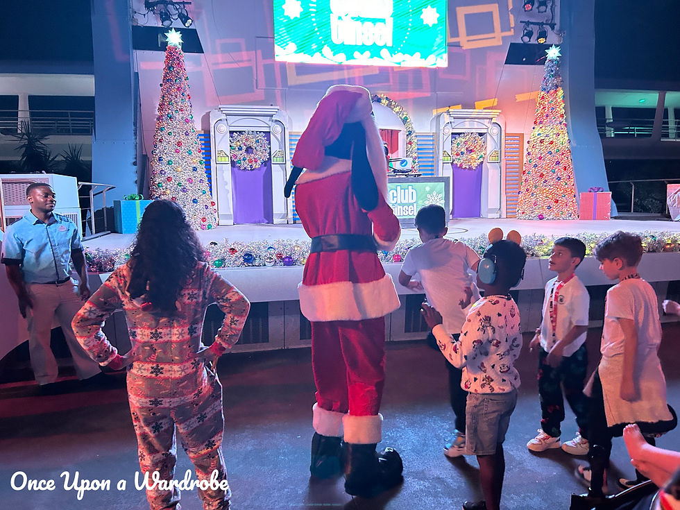 Children dance in pajamas and holiday outfits with Santa Goofy at the Club Tinsel stage during Mickey’s Very Merry Christmas Party.