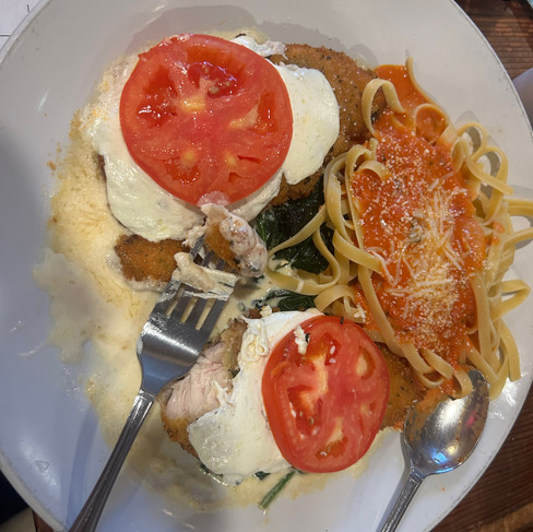 Dinner at PizzaOodles featuring chicken parmesan pasta with tomato sauce and a flatbread pizza topped with cheese, herbs, and vegetables