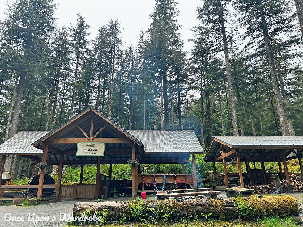 Wooden start and finish area for the Juneau sled dog musher's camp surrounded by tall evergreen trees.