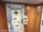 Disney Cruise stateroom door decorated with a Cinderella theme, blue fabric draping, clock door magnet, glass slipper details, princess magnets, and a hanging fish extender for cruise gifts.