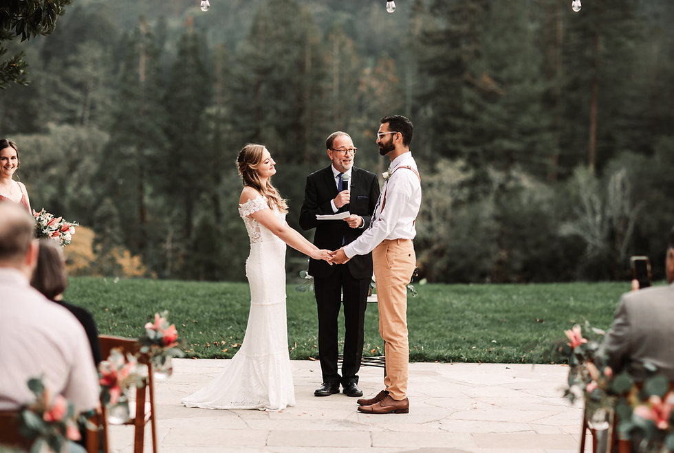 A wedding couple holding hands during their outdoor ceremony overlooking a forest background for their Wedding in Tahoe