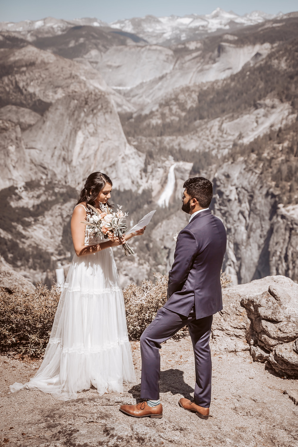 A elopement couple reading their vows in front of half dome at yosemite, these two asked themselves "should we elope" and did