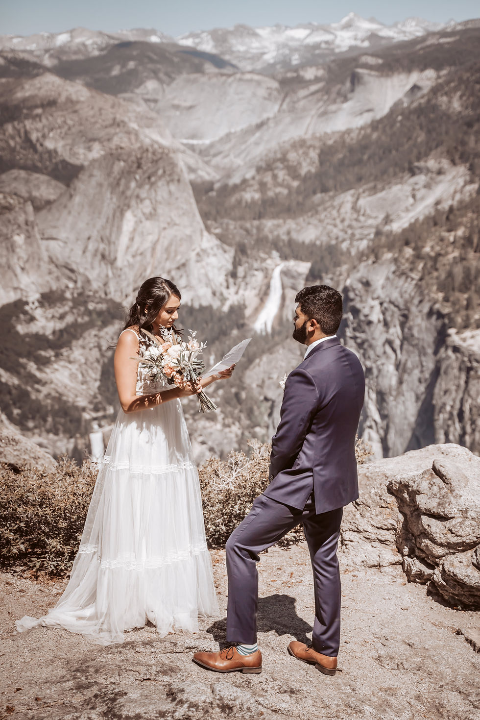 A elopement couple reading their vows in front of half dome at yosemite, these two asked themselves "should we elope" and did