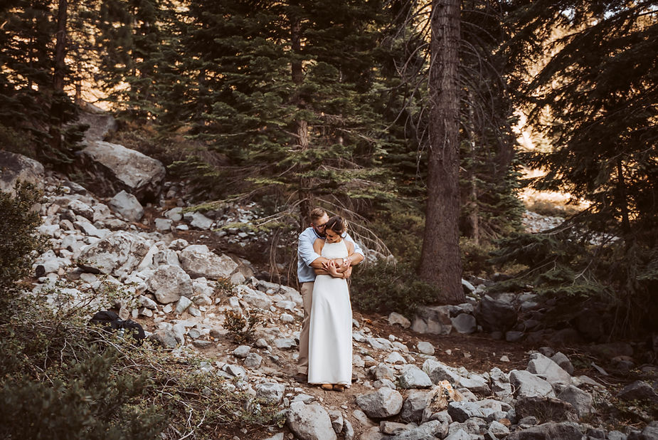 An elopement couple hugging under the giant pine trees of Lake Tahoe for their Elopement day in the Spring