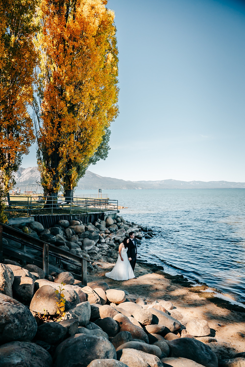 A wedding couple standing on the beach in Tahoe for their elopement day in the Fall