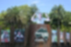 Entrance sign for Australia Zoo with "Home of the Crocodile Hunter". Features nature photos and a cutout of a man flexing, surrounded by lush greenery.