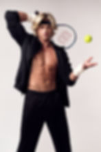 Deven Fagan with racket, black outfit, and headband, poised to hit a tennis ball. Neutral background, focused expression, athletic vibe.