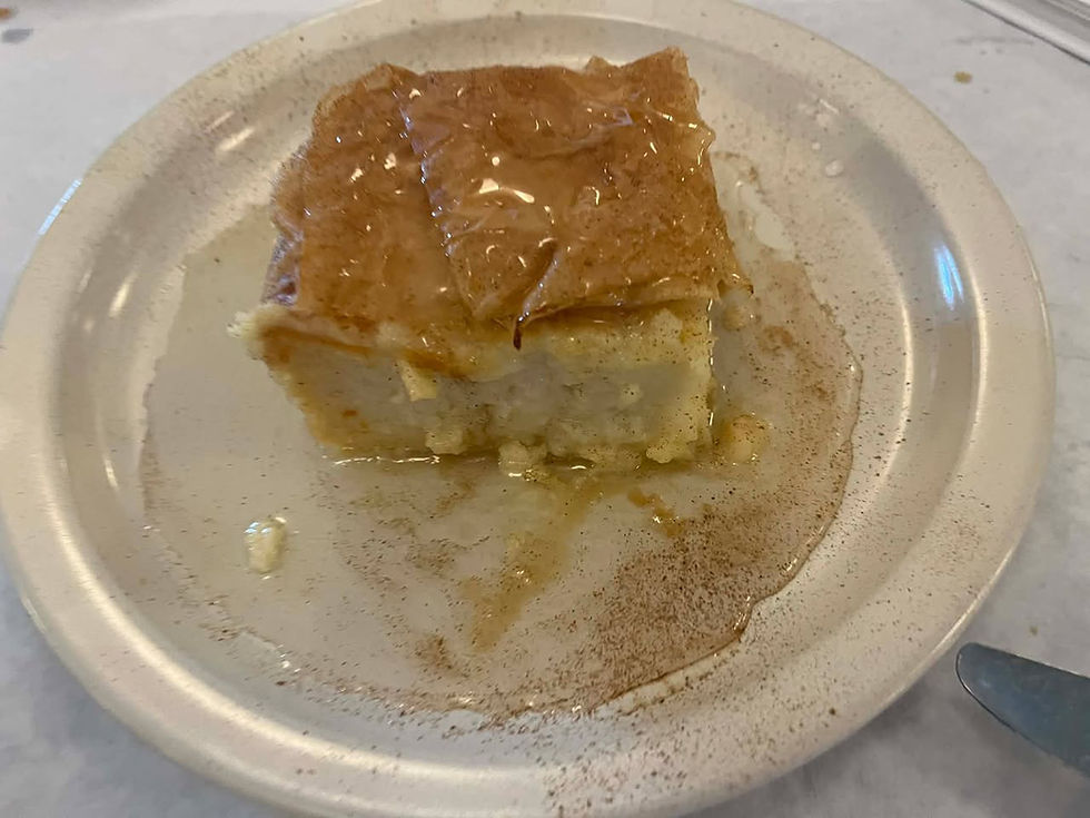 A square slice of honey-drizzled dessert on a beige plate, with a syrupy glaze and a dusting of cinnamon. White background.