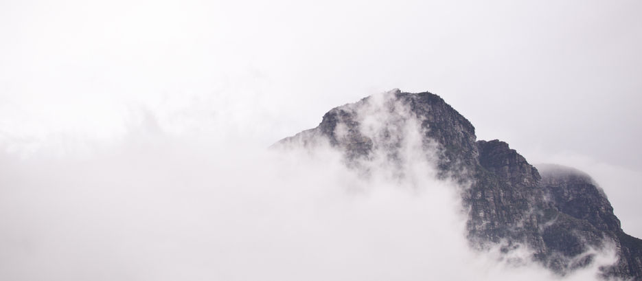 Imagem de montanha envolta por neblina, associada ao texto de Marisa Melo sobre criação artística como necessidade vital e desafio pessoal.