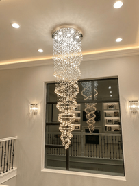 Luxury cascading spiral crystal raindrop chandelier lighting fixture professionally wired and installed in a high-ceiling foyer by All City Electric in Las Vegas.