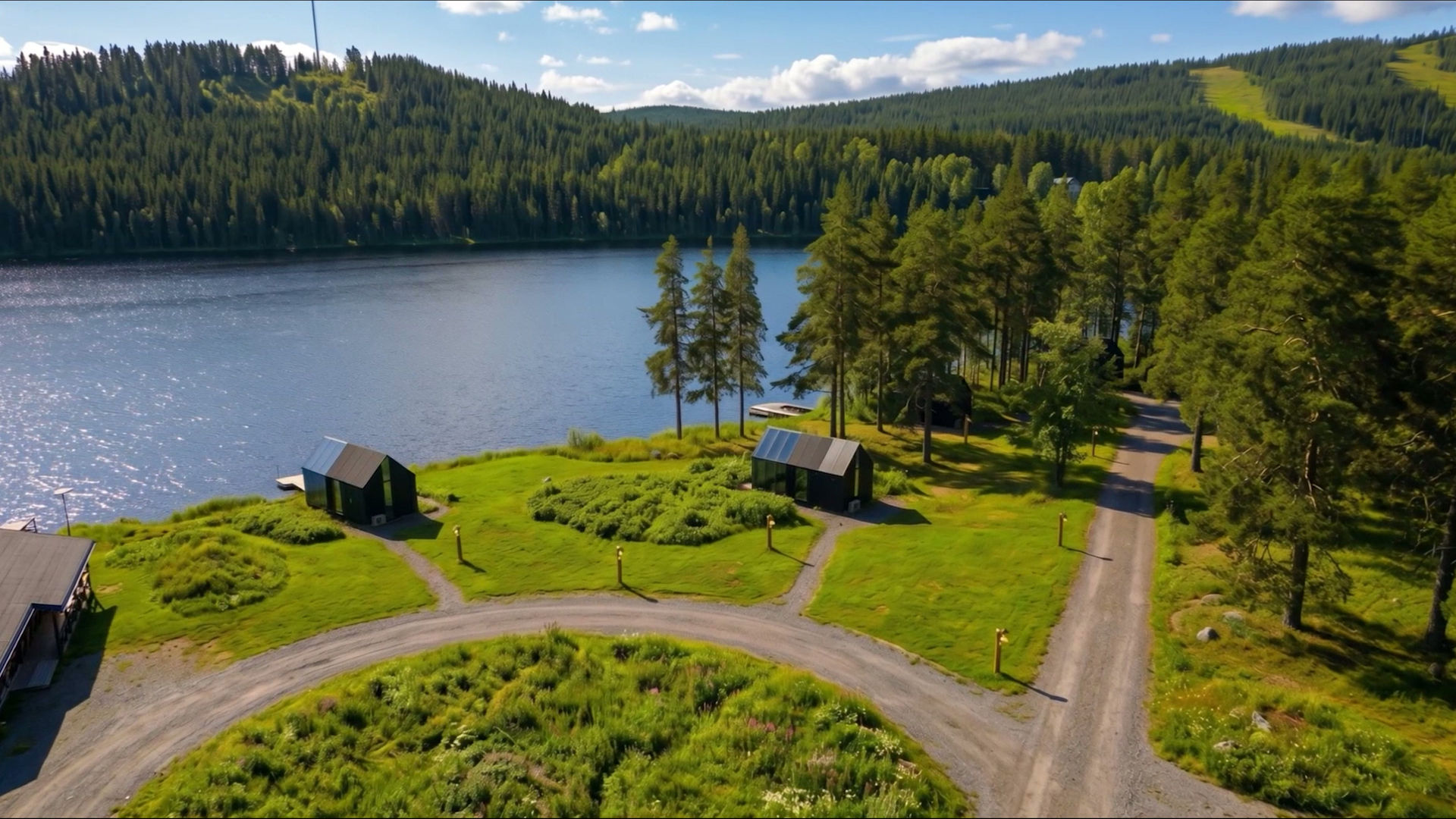 Midnight sun over the lake and forest surrounding the mirror glass cabins of Sameland Retreat in Swedish Lapland