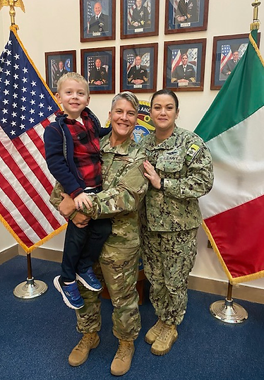 Bekah in her military uniform holding a child with another military woman