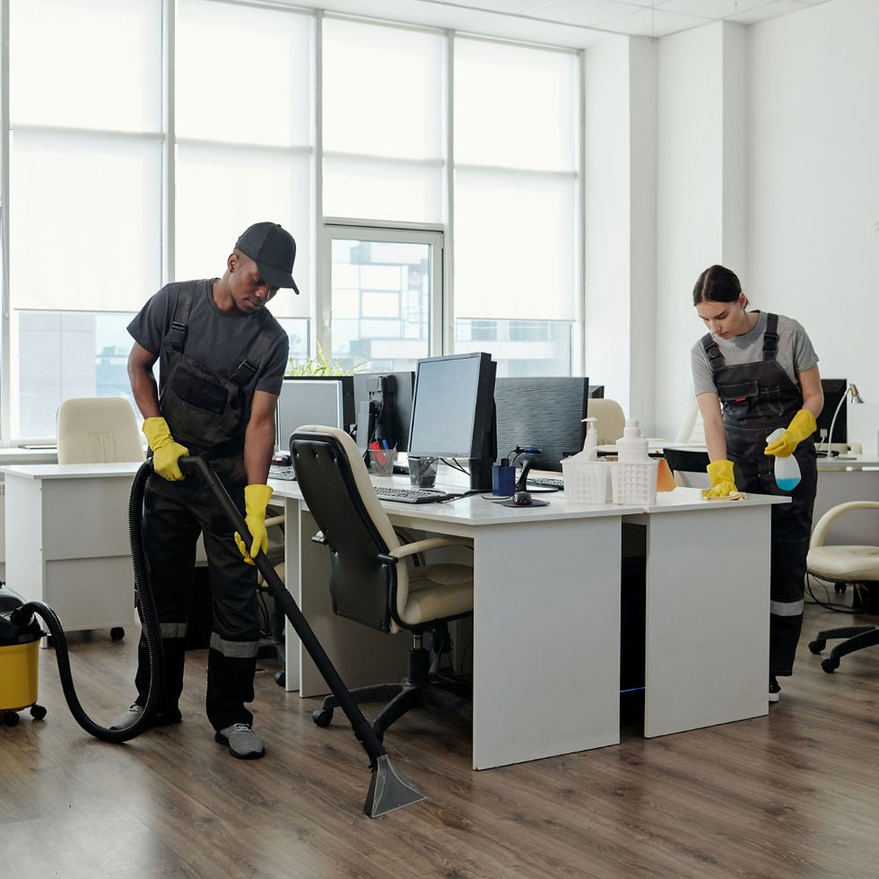 Two cleaners vacuuming and wiping desks in an office