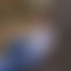 teenage boy sitting in front of a tree smiling at the camera