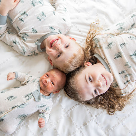 little kids laying on a bed looking up and smiling