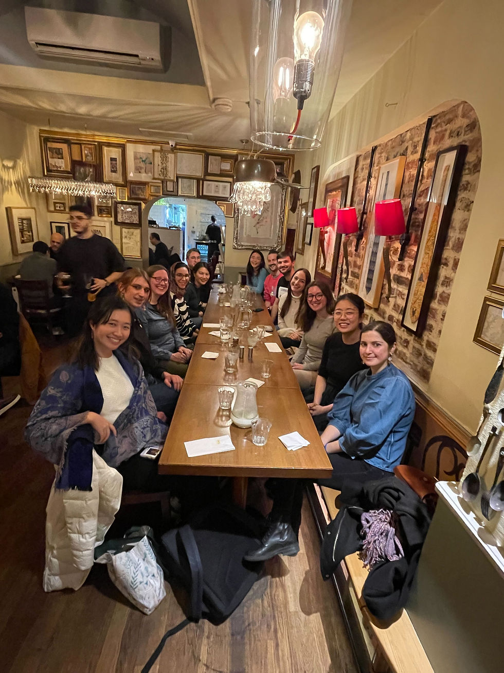 Lots of people sitting at a table smilling at the camera