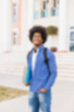 portrait-smiling-young-afro-male-student-holding-books-hand-standing-against-university-bu