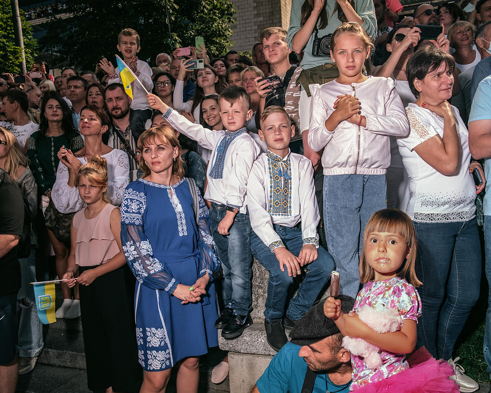 Dozens of Ukrainians stand in a crowd holding flags