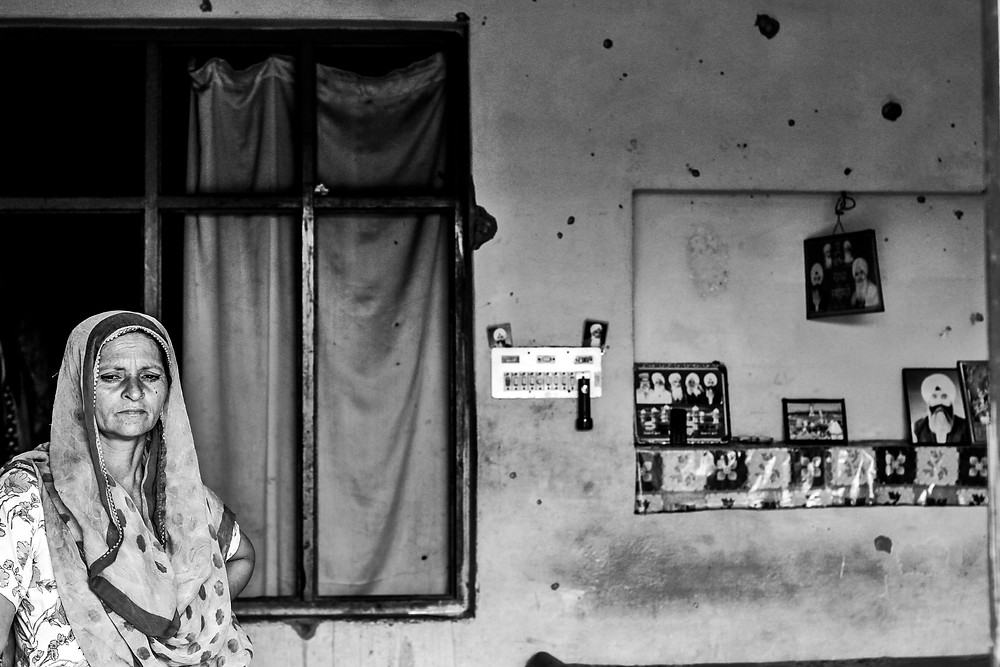A Kashmiri woman stands alone in her apartment.