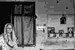 A Kashmiri woman stands alone in her apartment.