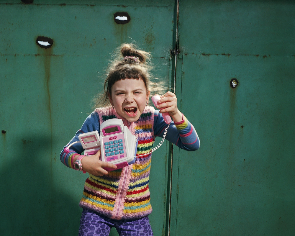 Thousands of children have been displaced by the Russian invasion of Ukraine (A little girl stands in front of a metal door with a toy telephone)