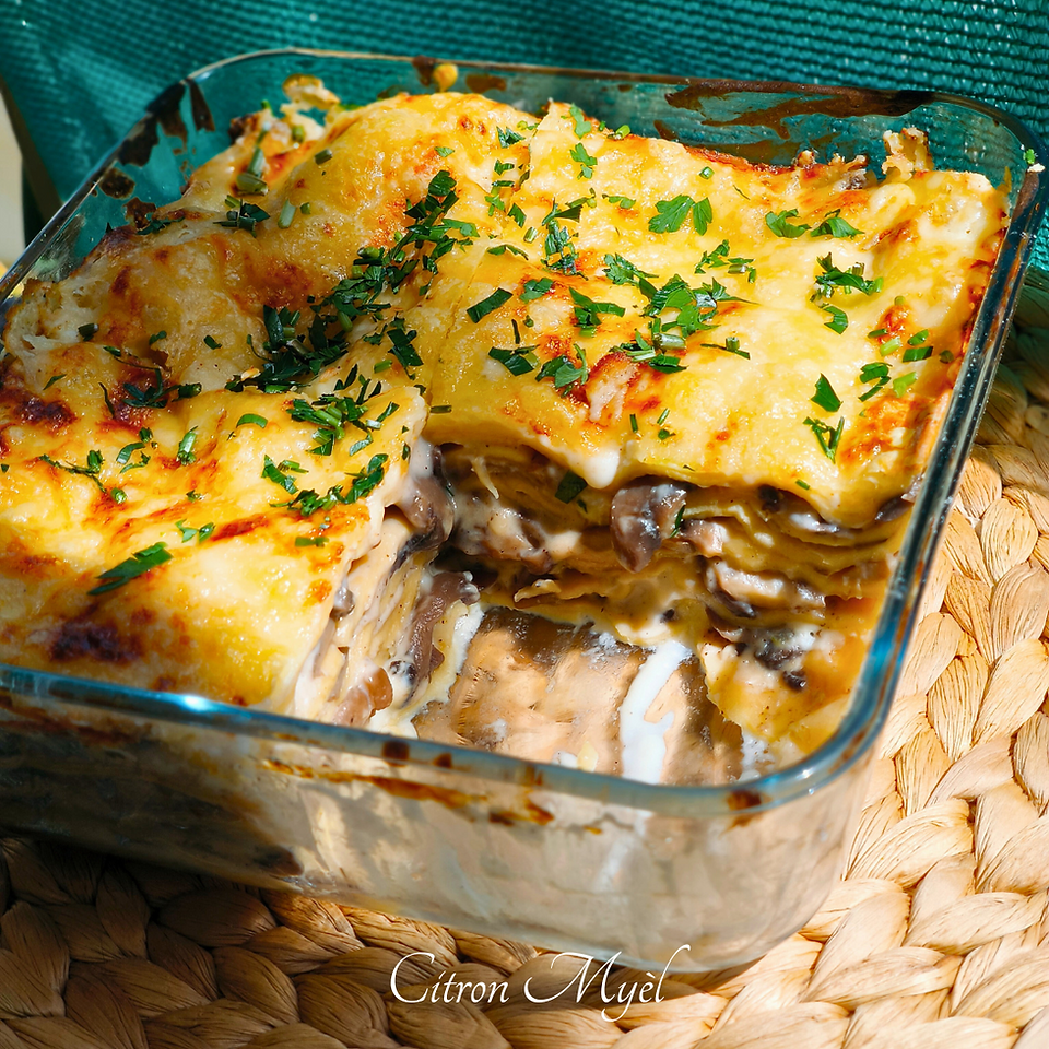 Plat de lasagnes aux champignons en verre avec une part en moins, deposé sur un set de table.