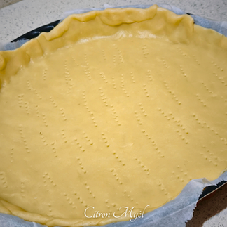 Pâte brisée dans un moule avec du papier cuisson.