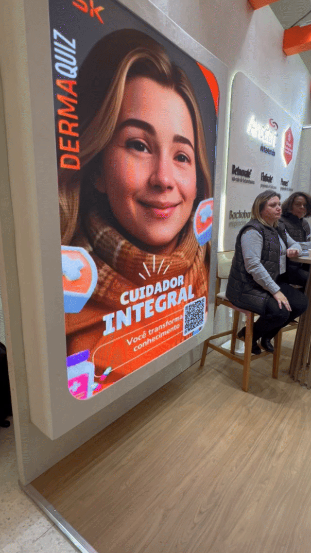 Visitante interage com totem Phygital no stand da GSK durante o TERADERM 2025, gerando avatar por IA e tendo sua imagem exibida na Social Wall em tempo real.