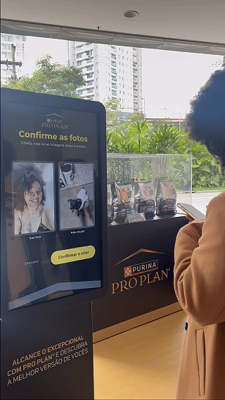 Totem interativo da ativação Nestlé Purina com QR Code para envio de fotos pelo celular. A experiência utilizava inteligência artificial para gerar uma imagem personalizada do tutor ao lado do seu pet, com resultado final direcionado para impressão.