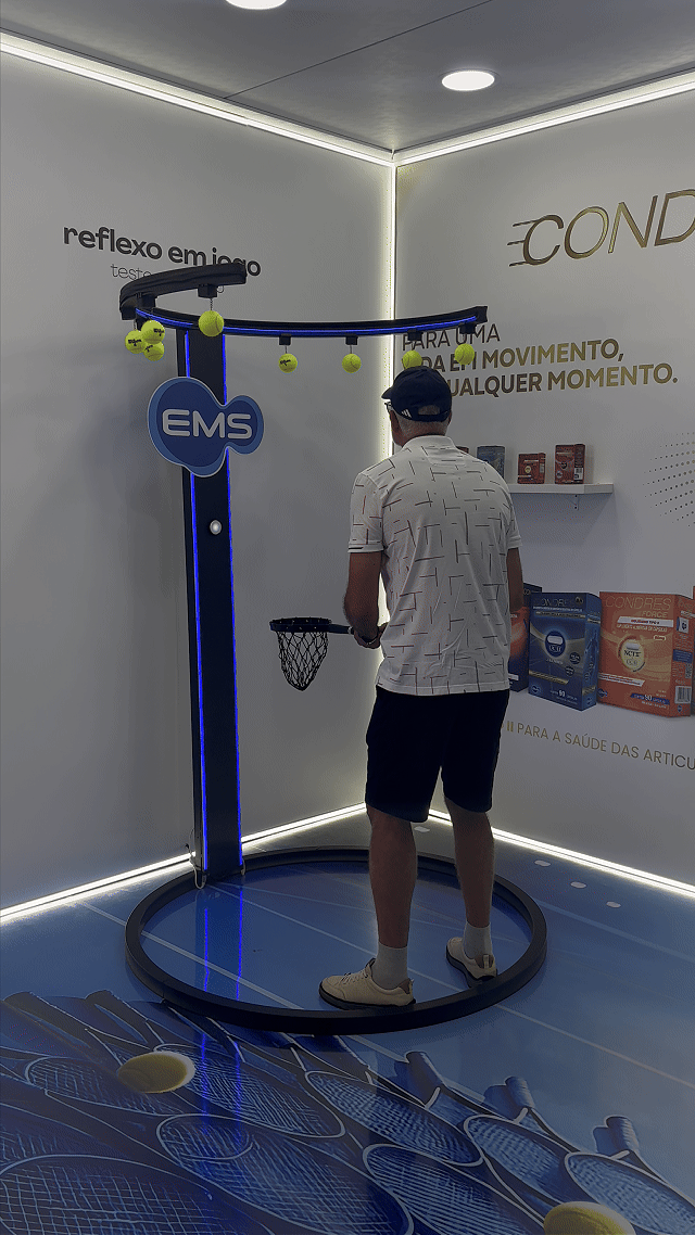 Ativação Reaction Ring no espaço da EMS durante o RIO OPEN 2026, com participante dentro da estrutura semicircular interativa enquanto o público acompanha ao redor em ambiente de evento esportivo.