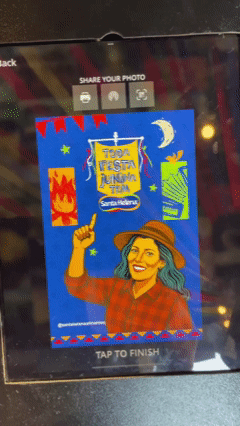 Participante tira foto no AI Booth da Santa Helena durante a Festa Junina do Clube Pinheiros e recebe imagem impressa no estilo Cordel.