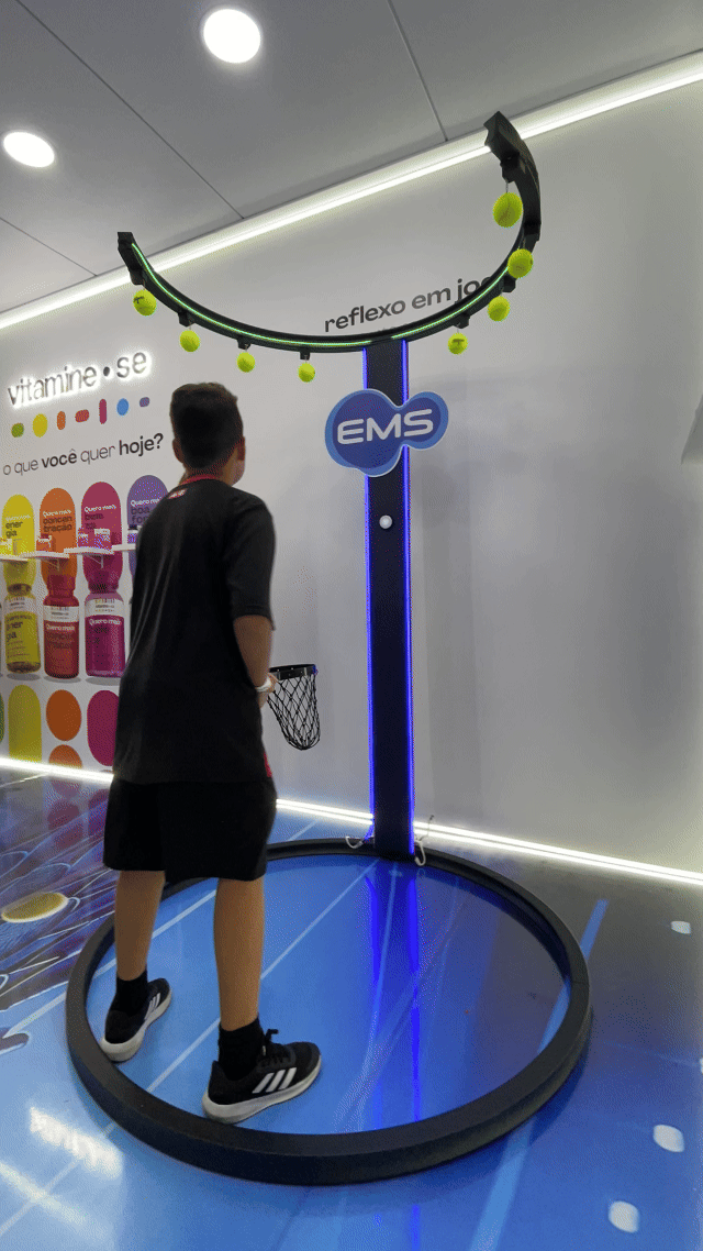 Ativação Reaction Ring no espaço da EMS durante o RIO OPEN 2026, com participante dentro da estrutura semicircular interativa enquanto o público acompanha ao redor em ambiente de evento esportivo.